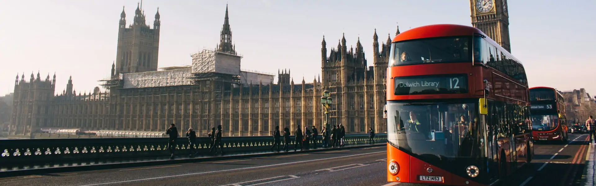 Red double-decker buses crossing Westminster Bridge with the Houses of Parliament and Big Ben behind